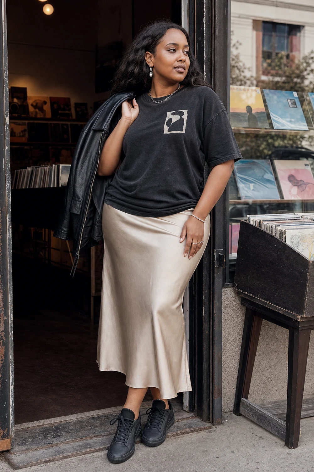 Plus size woman wearing a satin midi skirt with a graphic T-shirt and sneakers