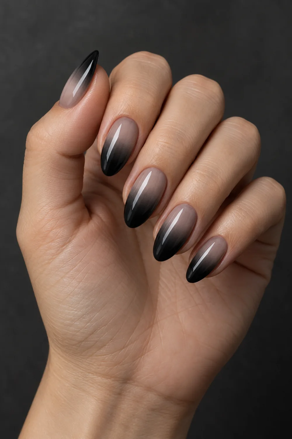 Sheer gray-nude almond nails fading into smoky black tips